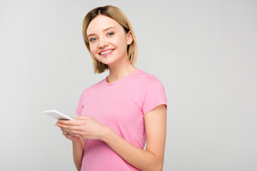 beautiful smiling girl in pink t-shirt using smartphone, isolated on grey