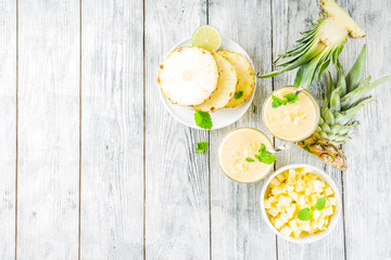 Homemade pineapple smoothie with fresh pineapple slices on wooden table, top view copy space