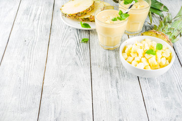 Homemade pineapple smoothie with fresh pineapple slices on wooden table, top view copy space