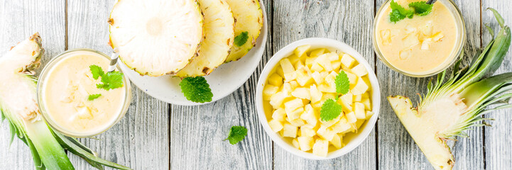 Homemade pineapple smoothie with fresh pineapple slices on wooden table, top view copy space