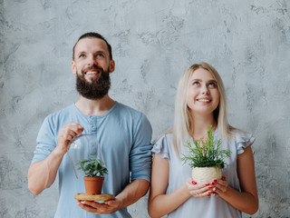 Plant care. Nature protection concept. Smiling environmentally friendly couple with houseplants.