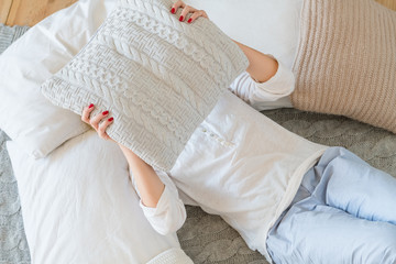 Leisure time. Home rest concept. Woman lying on bed and covering her face with pillow.