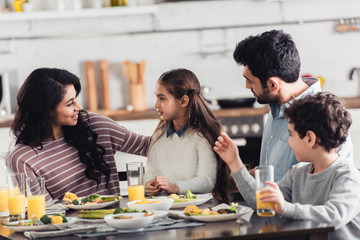attractive latin mother looking at daughter near husband and son at home