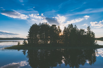 Bewaldete Insel spiegelt sich im Sonnenuntergang auf ruhigem See