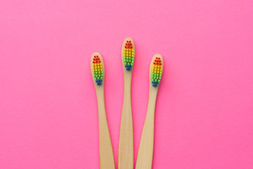 Photo of three toothbrushes with rainbow-colored bristles.