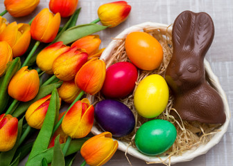 top view of colorful Easter eggs, chocolate bunny and tulip flowers
