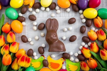 Easter background - colorful eggs, decorations, tulips, chocolate bunny and sweets
