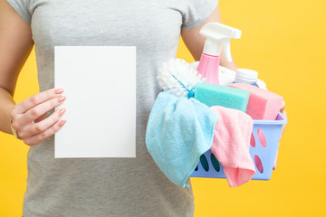 House cleaning checklist. Torso holding paper mockup and basket of supplies. Yellow background.