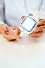 Photo of doctor's hand with glucometer.