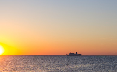 Naklejka na ściany i meble Cruise ship sailing in the sea at sunset 