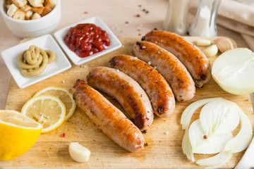 fried sausage, pork sausages with mustard ketchup, onions, lemon on a cutting Board