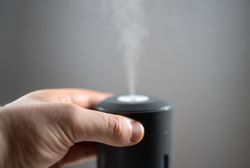 Man's hand turning on electric air humidifier.