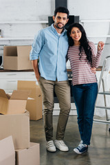 cheerful latin woman holding keys from new home near husband