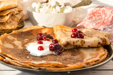 many pancakes with sour cream and cranberries on  plate, berries,