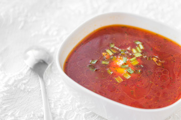 borscht with greens, red soup, 1 plate with soup, spoon, white tablecloth