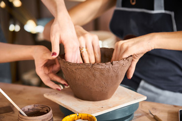 Woman making ceramic pottery, four hands close-up, focus on potters, palms with pottery, concept for workshop and master class