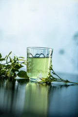Close up of extract of Indian jasmine flower or juhi or Jasminum Auriculatum on wooden surface in a transparent glass with raw flowers.