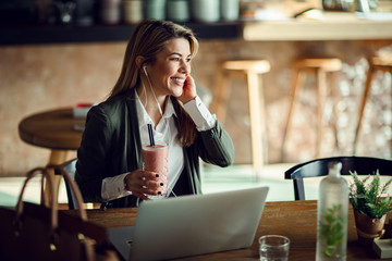 Happy businesswoman enjoying in good music and fruit smoothie in a cafe.