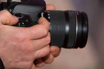 Fototapeta na wymiar Male hands holding a digital SLR camera close up