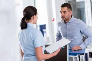 Stressed patient in blue shirt listening nurse in clinic