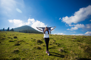 Hiking girl on top of hill with hands up enjoy mountain view.