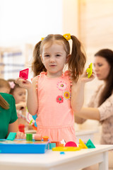 Child girl playing with blocks in kindergarten
