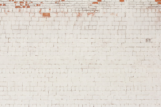 brick background, old brick wall painted white and with fallen off plaster