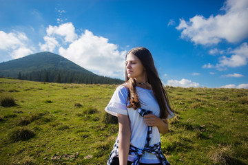 Young happy woman on top of hill enjoy beautiful view of sky and mountains, freedom concept