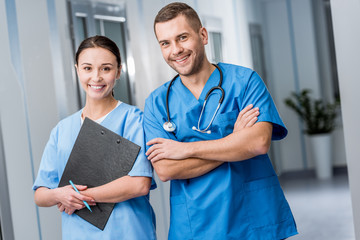 Smiling doctors in blue uniform holding stethoscope and clipboard