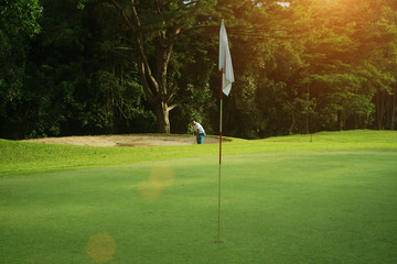 Obraz premium Blurred golfers are playing golf in the evening golf course, on sun set evening time.