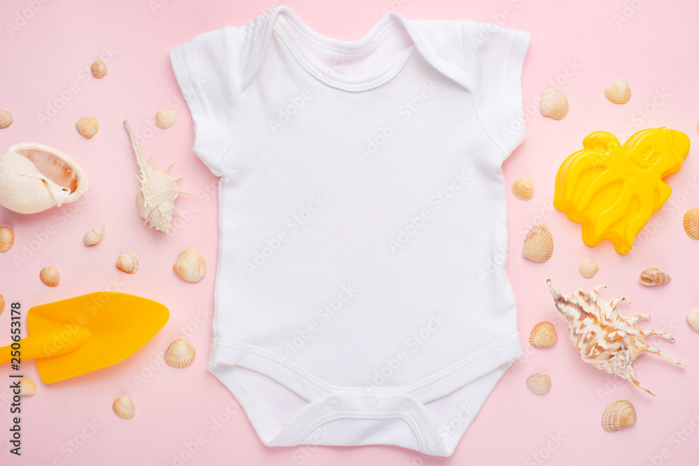 Wall mural Mockup Flat Lay white baby bodysuit shirt on a pink background with a nautical theme, shells and the sea with toys