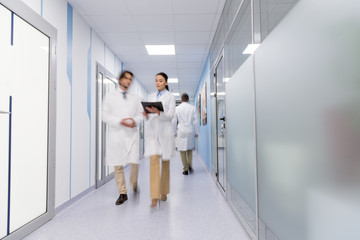 Doctors in white coats with black folder walking down hall