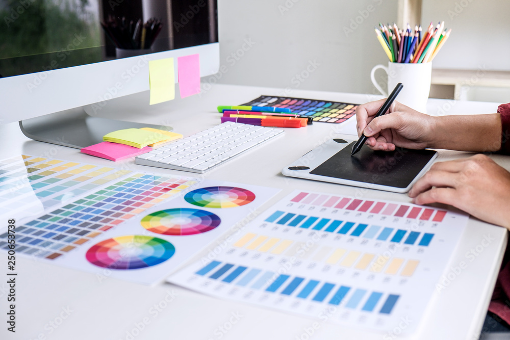 Poster image of female creative graphic designer working on color selection and drawing on graphics tablet 