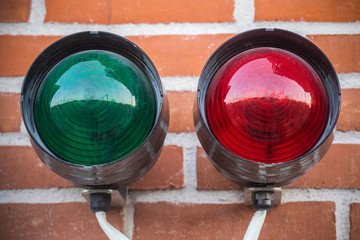 Two color traffic light on the red colored brick wall