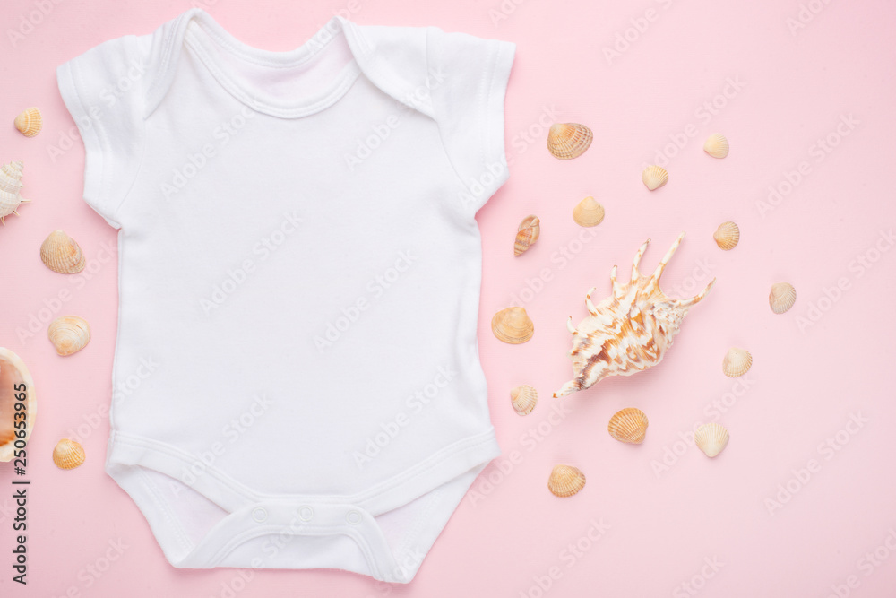 Wall mural Mockup Flat Lay white baby bodysuit shirt on a pink background with a nautical theme, shells and the sea