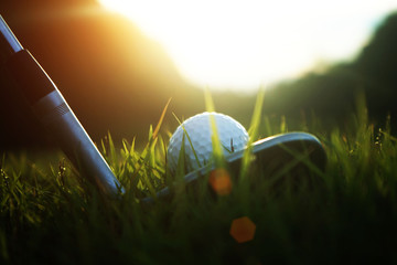 golf club and golf ball close up in grass field with sunset. Golf ball close up in golf coures at...