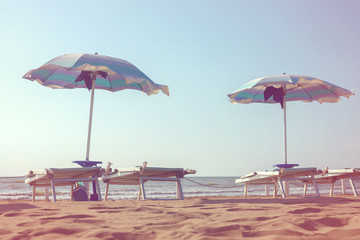 sun beds under umbrellas on the first line of the beach, toned