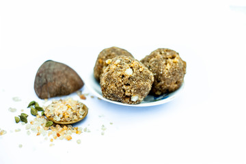 Close up of popular Indian & Asian sweet dish i.e. Malida or churma na ladu or moti chur na ladu in a glass plate with entire ingredients including fry fruits isolated on white.;