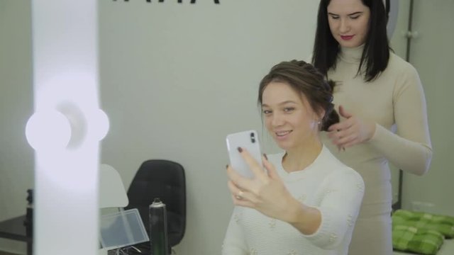 Very beautiful and modern woman makes a selfie when she does her hair in a beauty salon.