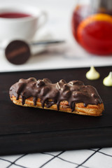 French eclair with caramel on the wood plank
