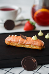 French eclair with mango on the wood plank