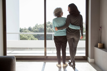 Rear view of happy mother and daughter standing embracing