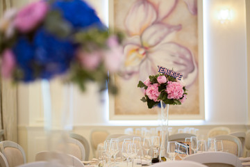 Interior. round table and chair with white table cloth combined by flower bouquet on tall