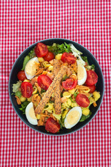 Salad of pasta, egg, smoked salmon tartare, salad and tomato, with a citrus vinaigrette sauce.