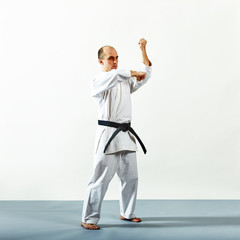 Fototapeta na wymiar Black belt athlete doing formal exercises on a gray cover