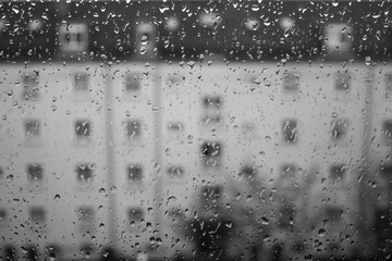 Drops of rain on glass , rain drops on clear window. Water condensation on transparent glass over city landscape or building in blur. Monochromatic - 250663751