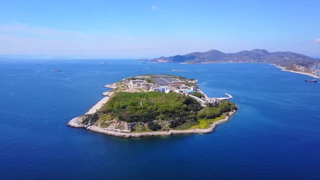 Aerial drone bird's eye video from island of Psytaleia the largest sewage treatment plant in Europe, Saronic gulf, Peiraeus, Attica, Greece