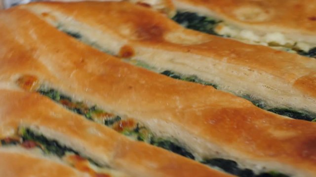 Closeup georgian bakery chef demonstrates just baked khachapuri with cheese spinache