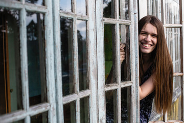 Young woman with long hair looks out of the window.