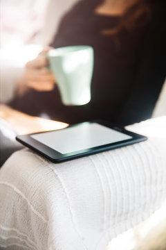 Young woman drinking coffee and using an ebook reader